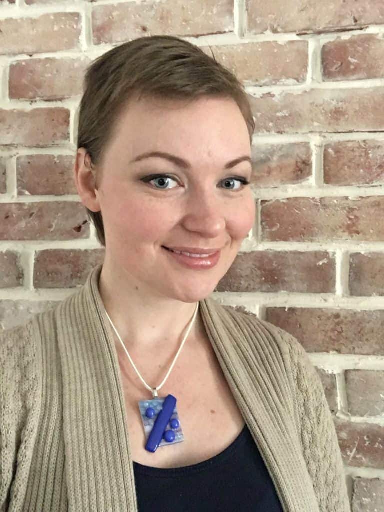 Girl with short brown hair in front of brick wall.