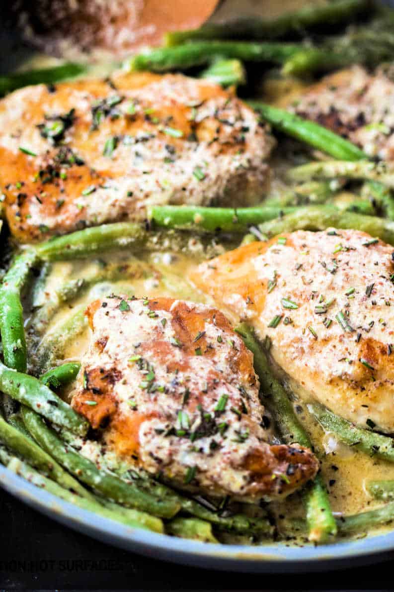 chicken simmering with green beans in a fry pan
