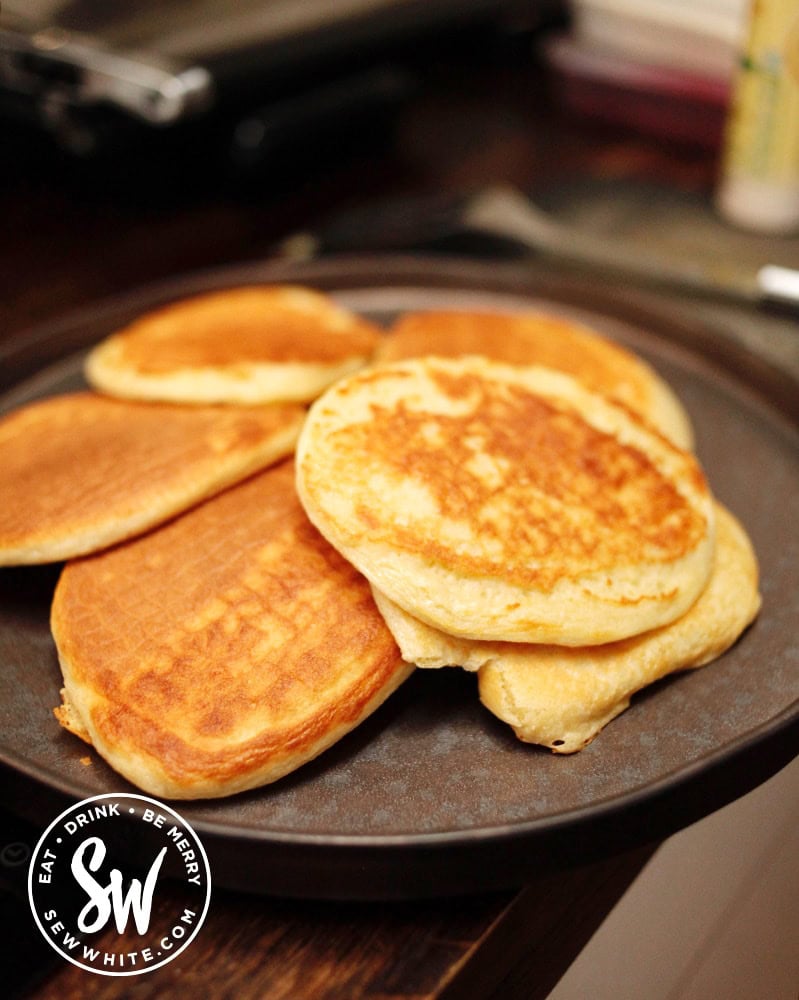 A pile of Scotch Pancakes on a black plate
