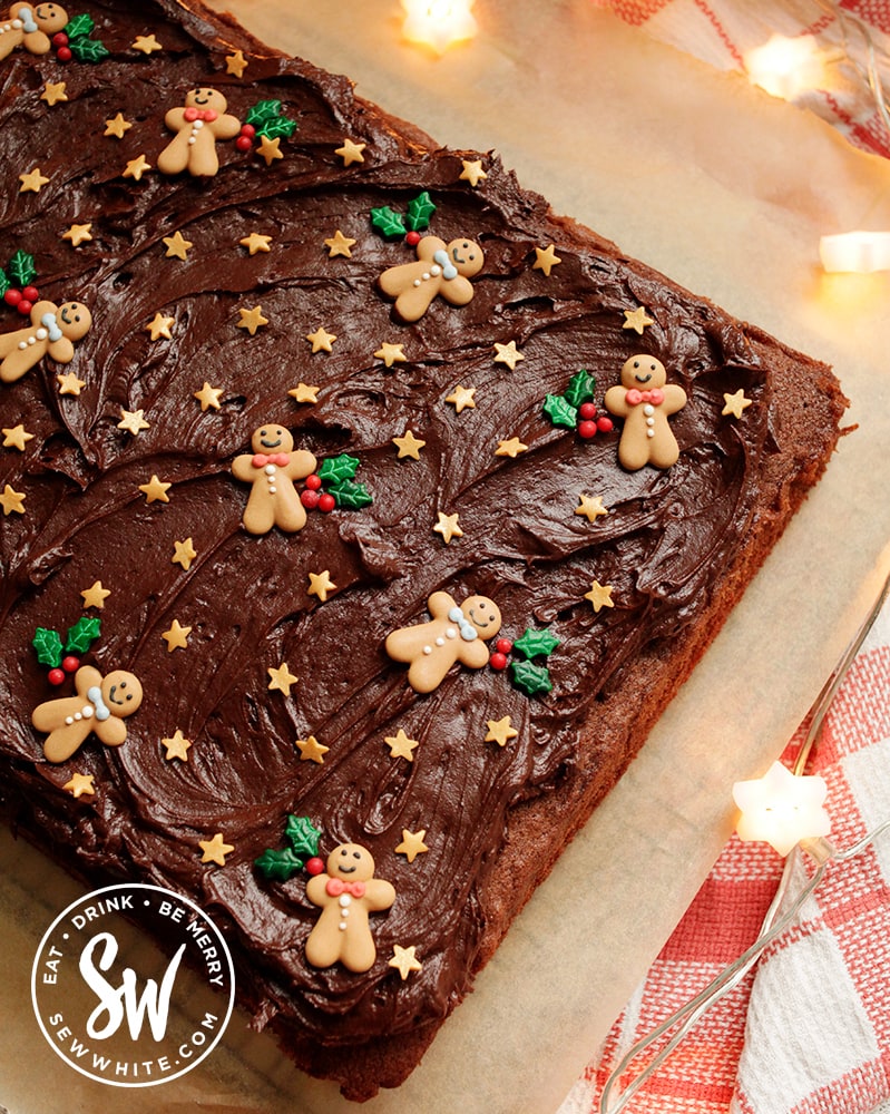 easy chocolate traybake for Christmas on a sheet of greaseproof paper with chocolate buttercream topping and sprinkles.