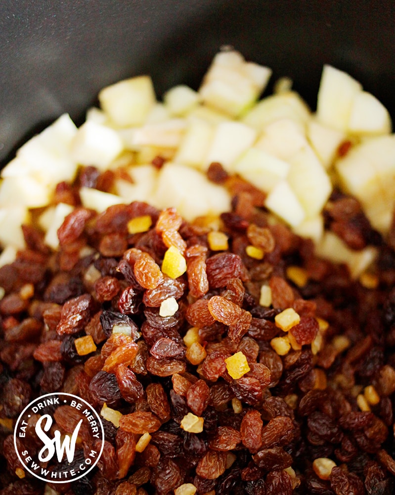 mixed berries being added to the apple in the slow cooker to make vegan mincemeat