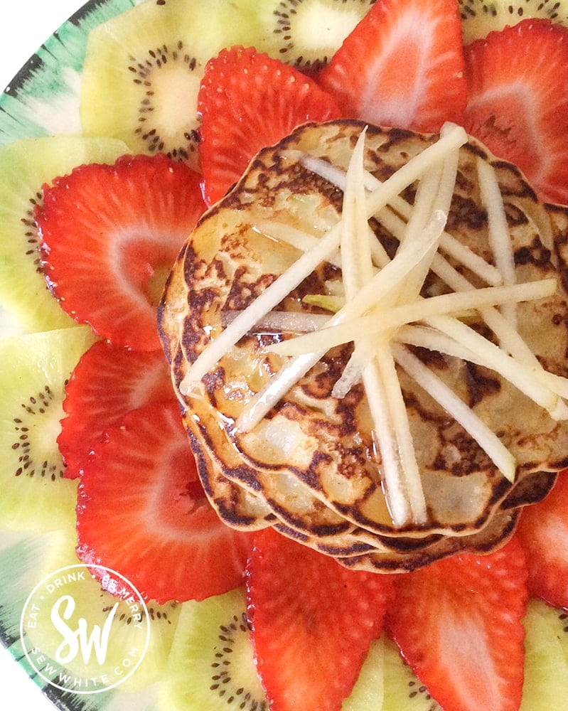 golden brown fluffy apple pancakes topped with grated apple and maple syrup