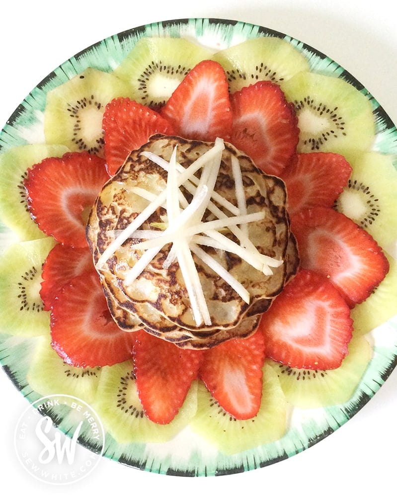Apple pancakes on a white and green plate on a white table ready to be served.