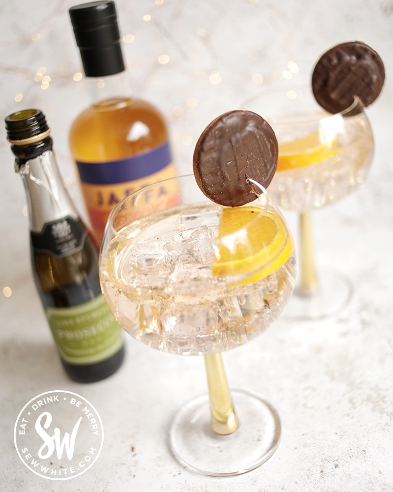 Jaffa Cake Gin Spritz in gold stemmed glasses, decorated with jaffa cakes
