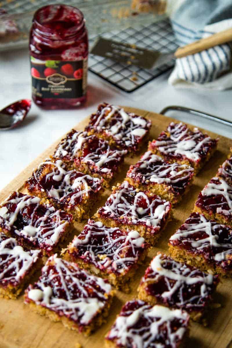 raspberry oatmeal bars on a wooden cutting board with raspberry jam