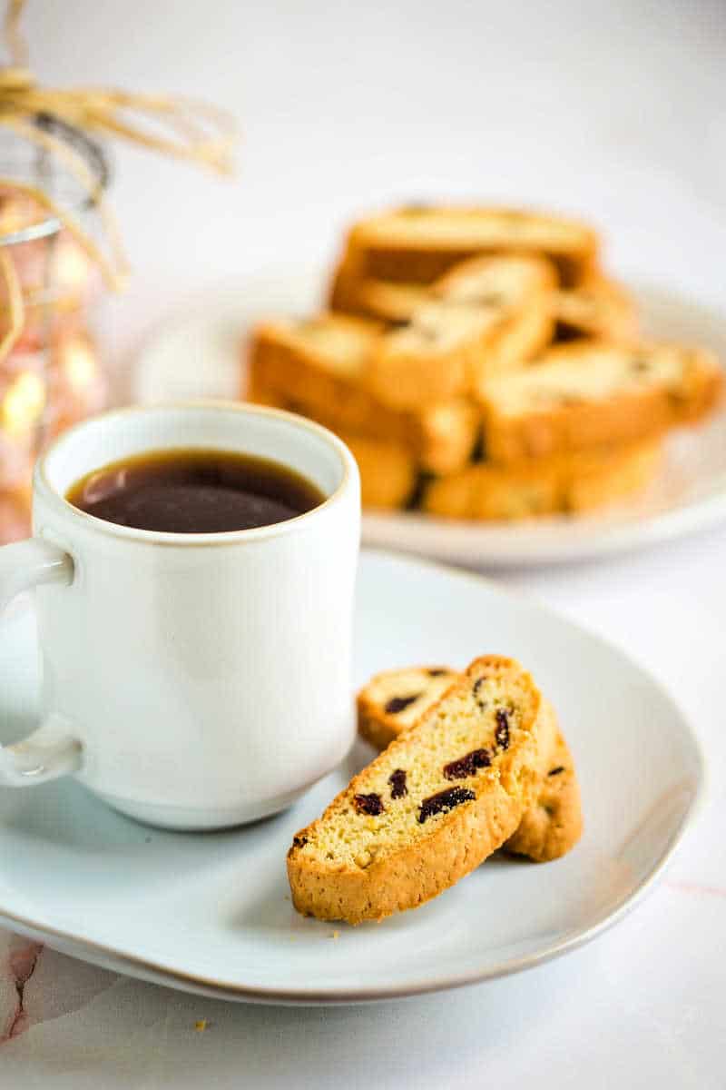cherry biscotti on a plate with a cup of coffee