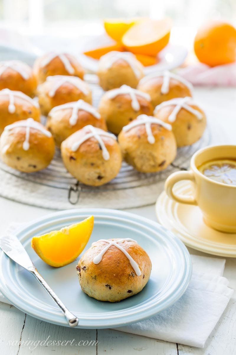 homemade hot cross buns with orange slices and a cup of tea with lemon