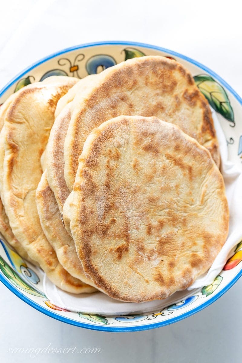 Try this easy homemade whole wheat pita recipe next time you crave tender, chewy pitas with a touch of honey for sweetness. #pitabread #pitarecipe #pita #flatbread #middleeasternbread #Greekfood #easypitabread #howtomakepitabread #pitabreadrecipe A bowl of fresh homemade whole wheat pita bread