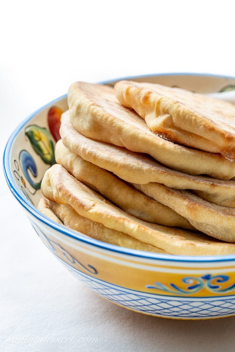 Try this easy homemade whole wheat pita recipe next time you crave tender, chewy pitas with a touch of honey for sweetness. #pitabread #pitarecipe #pita #flatbread #middleeasternbread #Greekfood #easypitabread #howtomakepitabread #pitabreadrecipe A bowl of fresh homemade whole wheat pita breads