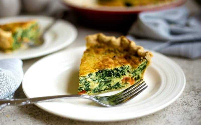slice of spinach quiche on a white plate