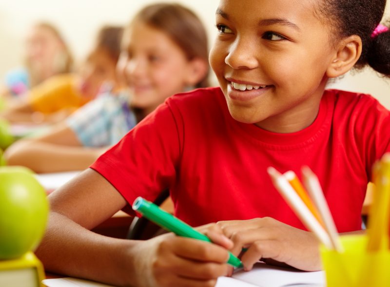 child holding a pen and looking up towards teacher