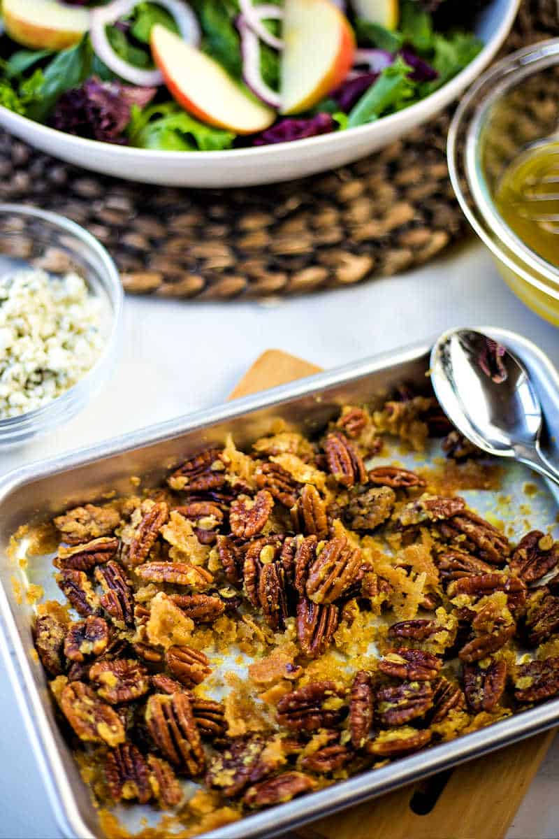 a baking sheet with sugared pecans on a trivet