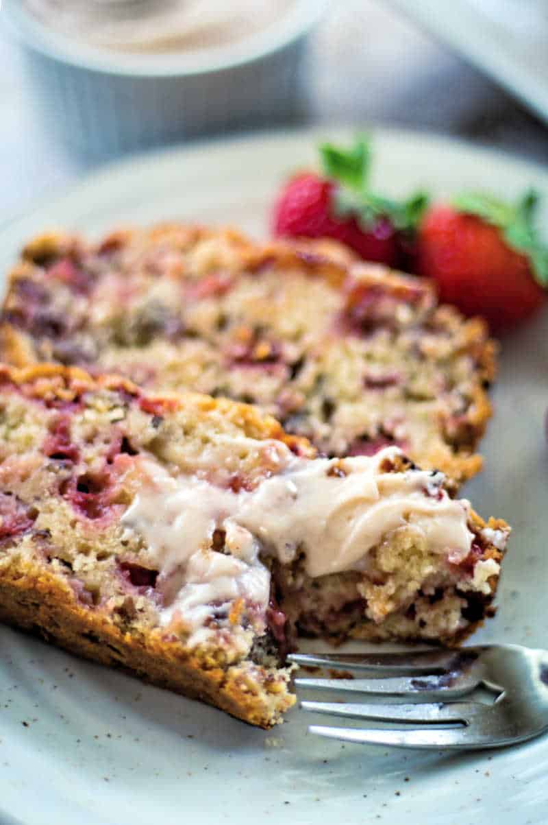 slices of strawberry bread on a plate with a fork and a smear of butter