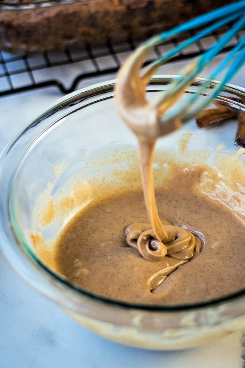 a whisk swirling cinnamon glaze in a glass bowl