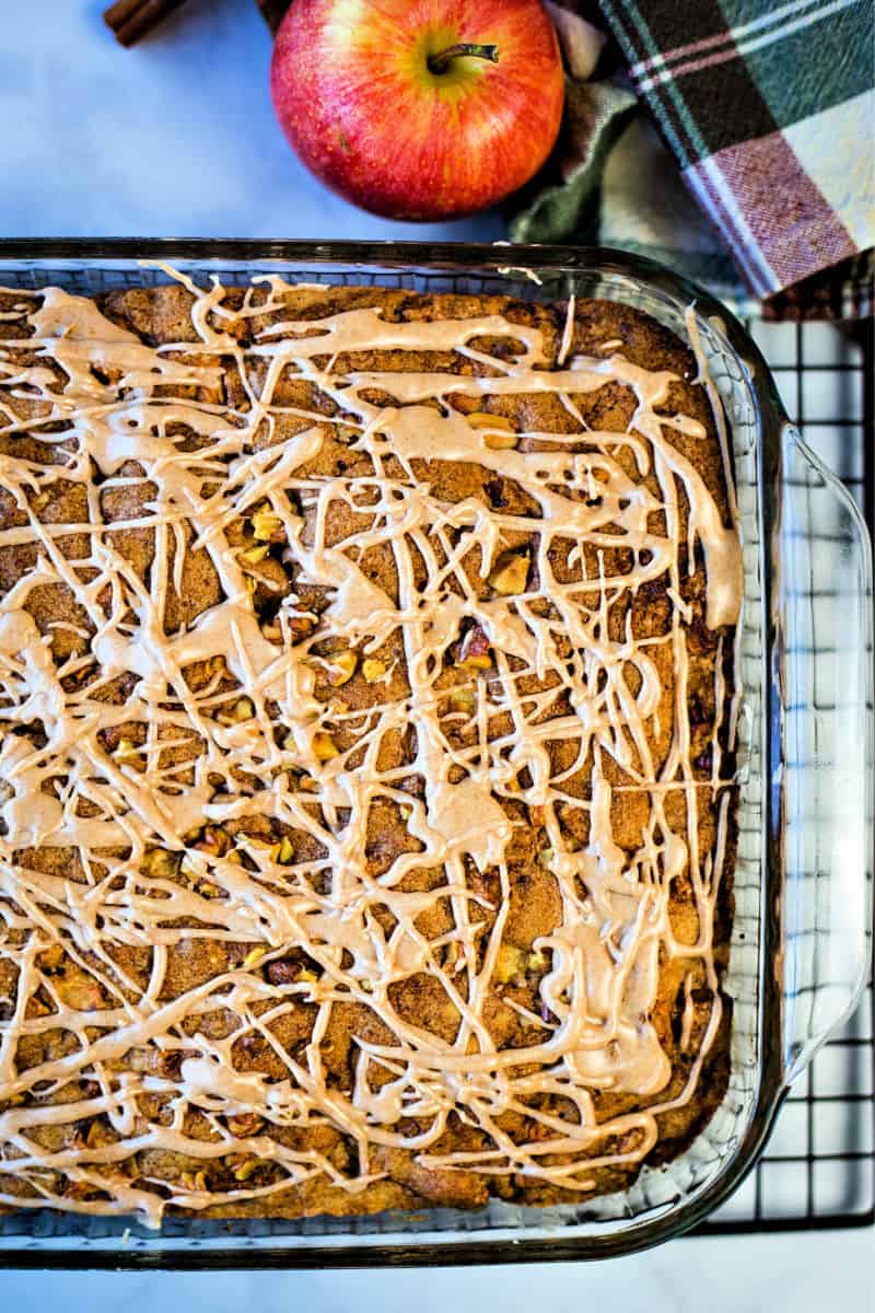 fresh apple cake in a glass cake pan on a wire rack