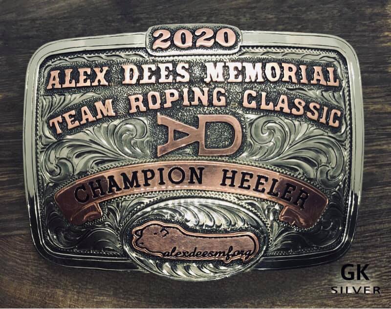 Close up image of handmade belt buckle which reads: "Alex Dees Memorial Team Roping Classic Champion Heeler"