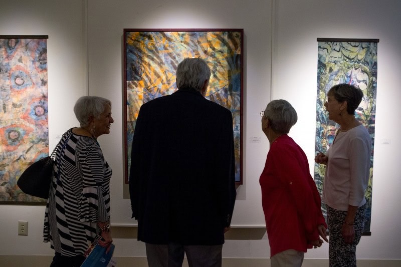 Patrons and a docent look at a painting in the Brenau Presidents Gallery.