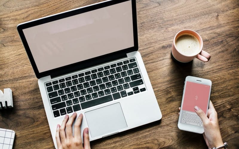 laptop on desk with pink mobile screen_blog_content_planner