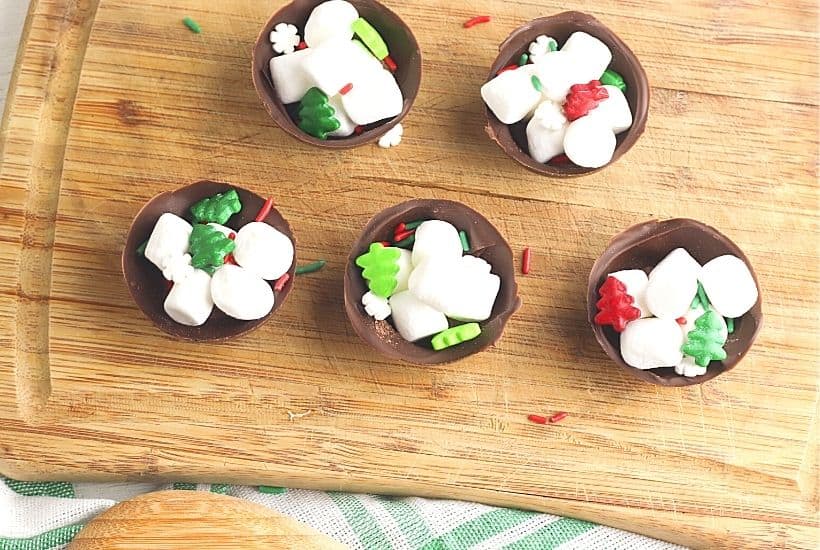 Ready for an indulgent treat? This Hot Chocolate Bombs Recipe is rich and filled with hot chocolate, marshmallow and sprinkle surprises inside. What is a hot chocolate bomb? A Hot cocoa bomb is a chocolate shell that is filled with hot cocoa, marshmallows and other hot chocolate add ins. Download the free Christmas printable gift bag toppers and give these as a Christmas food gift.