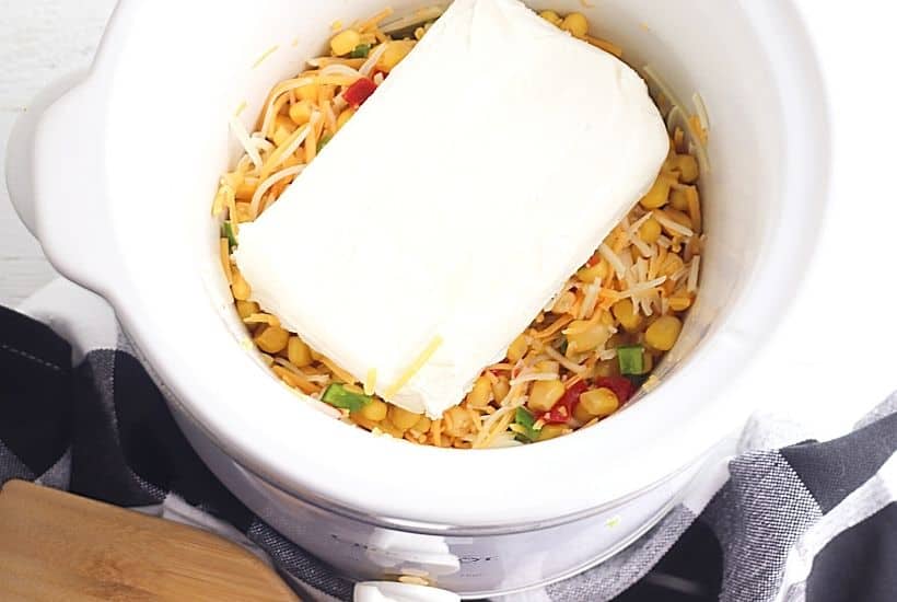 This Cheesy Slow Cooker Fiesta Corn Dip is a creamy, cheesy dip recipe that's perfect for any party. It's great for tailgating, too!