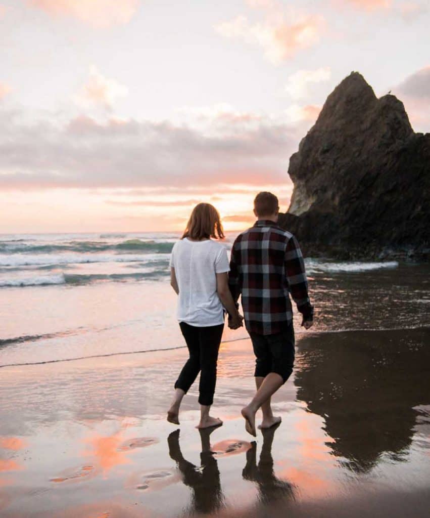 Man and women walking on beach at sunset after marriage proposal