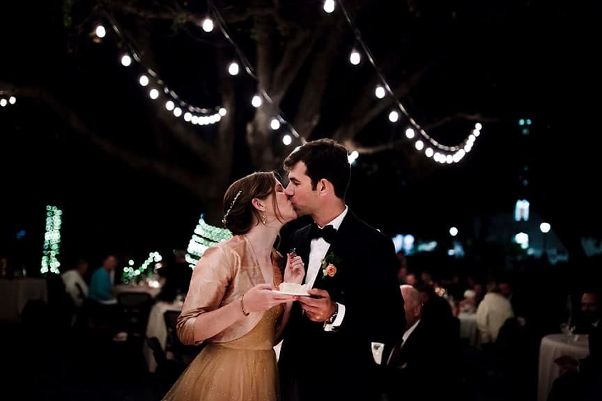 Bride and groom kissing whilst holding wedding cake