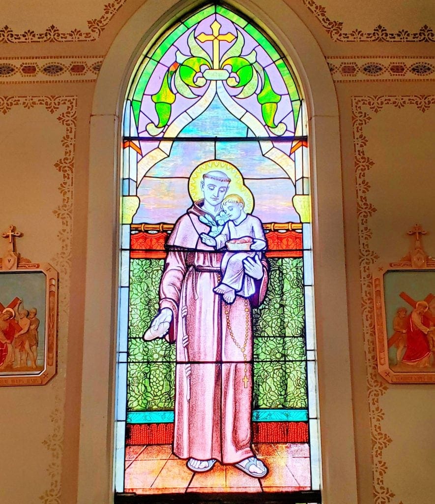 stained glass window at St Matthias Church that depicts St Anthony holding the Christ child and bread