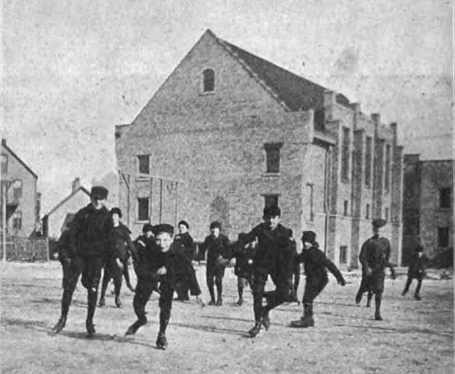 Photograph of children playing at the University of Chicago Settlement, captioned "Gymnasium of University Settlement." From page 388 of The Kindergarten Teacher, vol. 13, 1900-1901. Sourced from the Wikimedia Commons where it is said to be in the public domain.