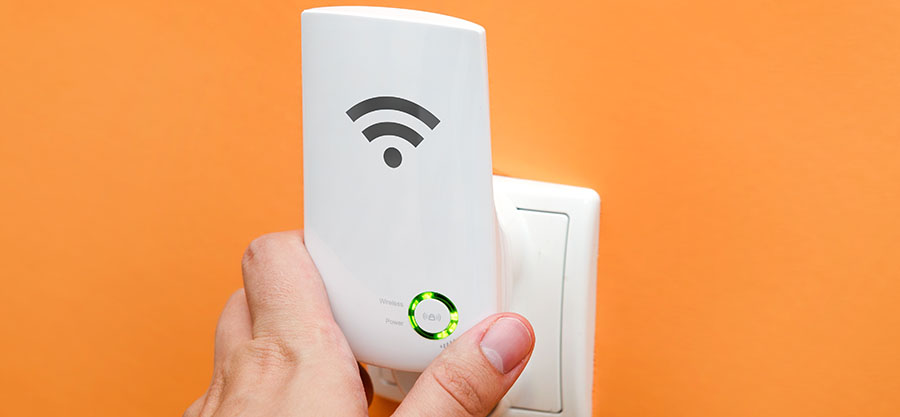 WiFi repeater in electrical socket on orange wall. Simply way to extend wireless network in home