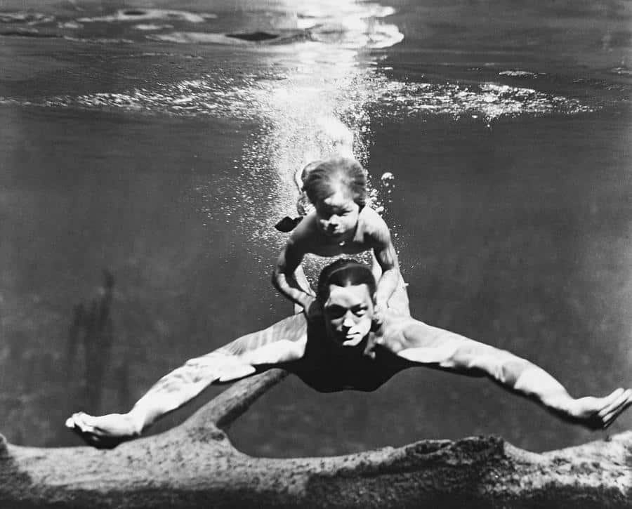 Johnny Weissmuller professional swimmer and actor, swimming with a child
