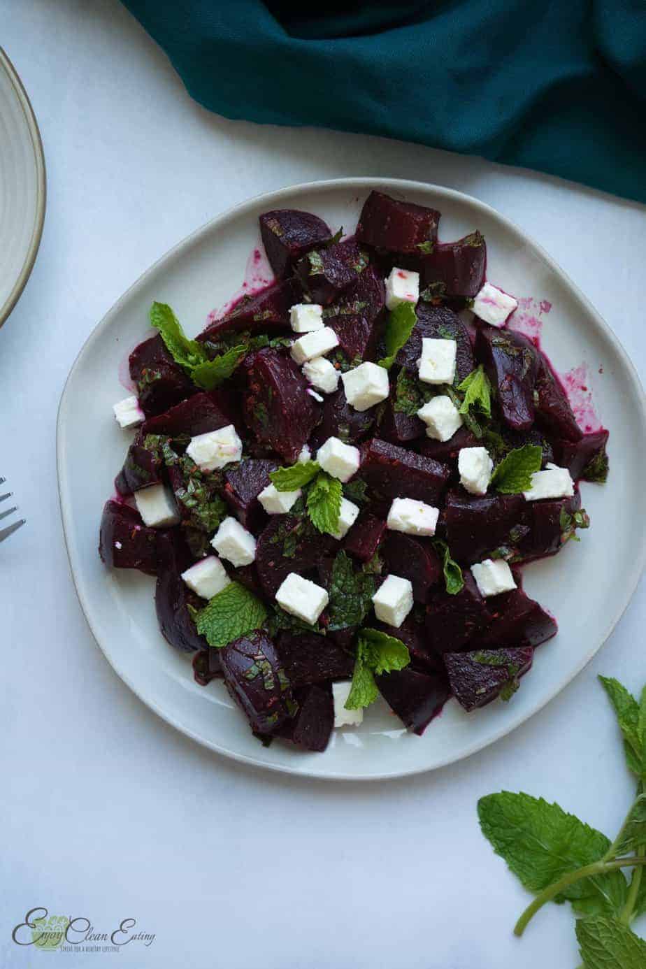 beet salad with feta cheese on a plate. a fork, small serving plate and napkins
