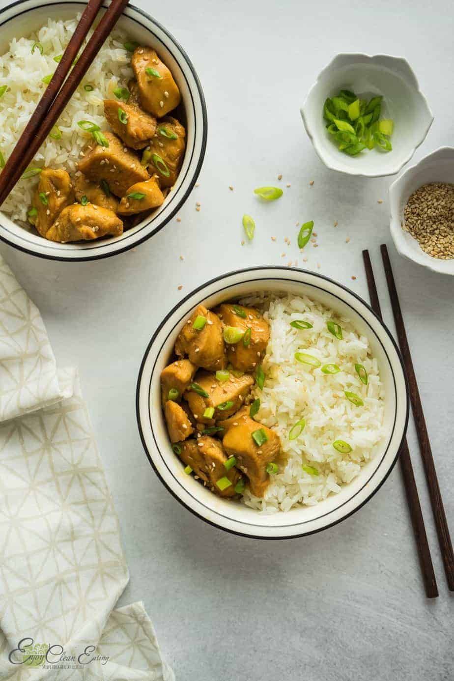 two bowls with white rice, pressure cooker chicken teriyaki with sesame seeds and green onion sprinkle over the rice and chicken pieces.