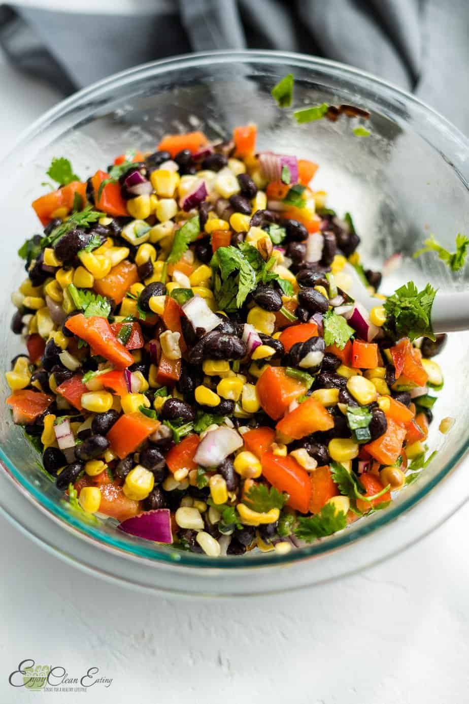 corn and black bean salsa in a mixing bowl with a spoon