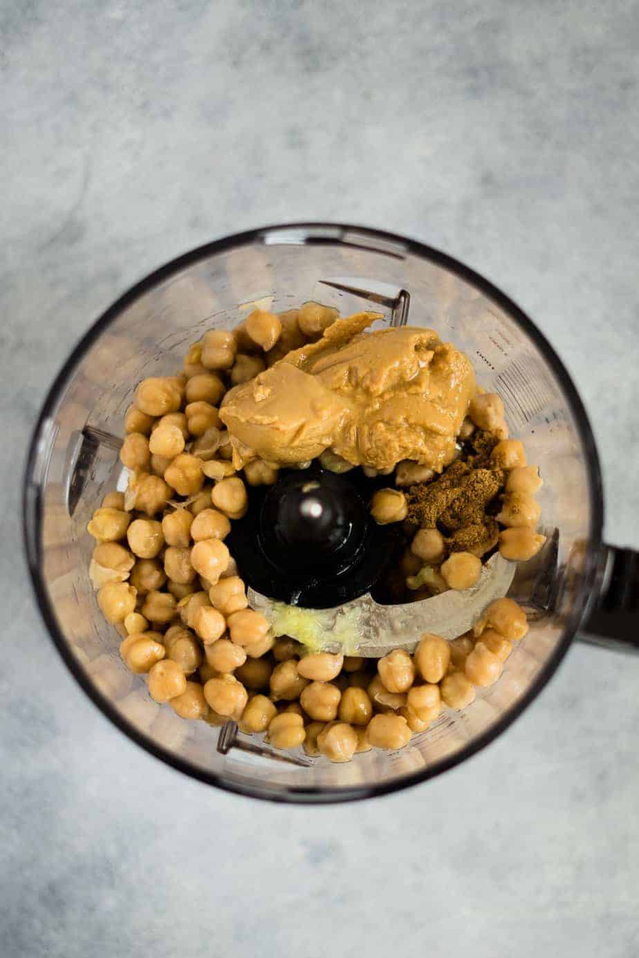 garbanzo beans inside the ninja food processor with the ingredients to make instant pot hummus