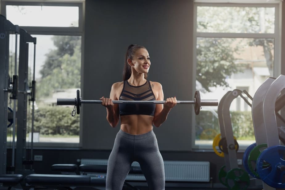 A girl has a training with weights at the gym