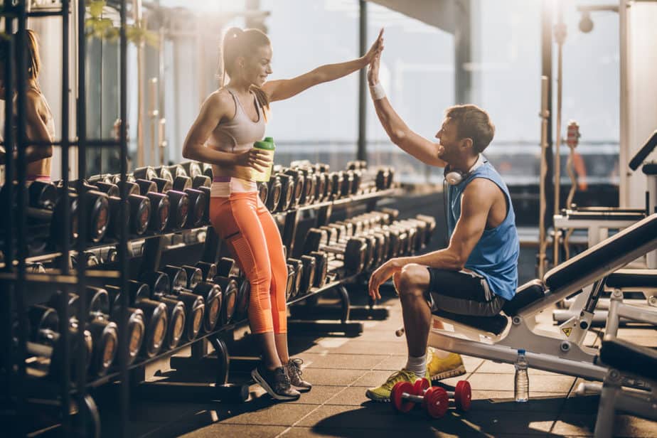 A girl and boy are supporting each other at the gym