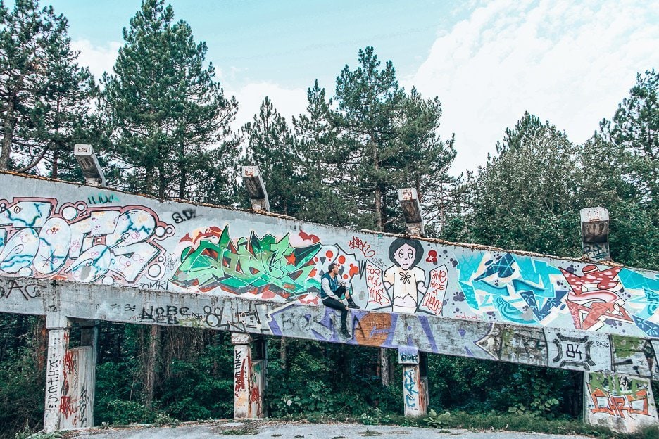 12 Bucket List Destinations The Best Hidden Gems in Europe for 2020 14 L Bevan of the Travel Quandary sits in front of the graffiti on the abandoned bobsled track in Sarajevo, Bosnia & Herzegovina