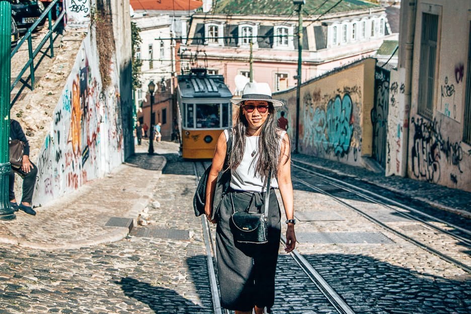 7 Useful Tips To Follow To Avoid Pickpockets 2 L Walking up a cobblestoned hill in front of a yellow tram in Lisbon, Portugal