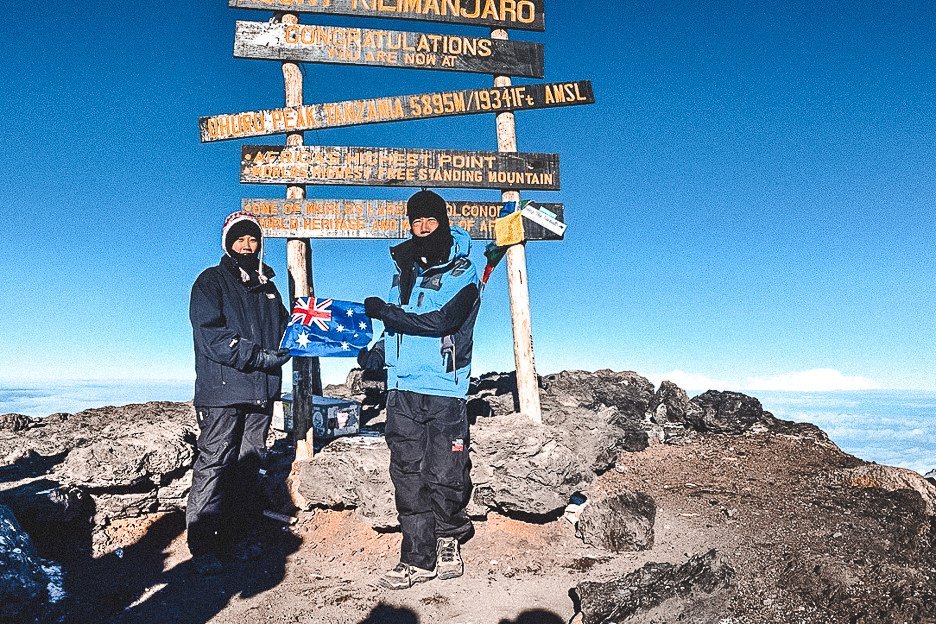 How I Summitted Kilimanjaro The Machame Route In 7 Days 20 L Jasmine standing with her dad holding an Australian flag at the top of Mt Kilimanjaro
