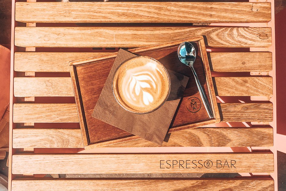 6 Amazing Third Wave Coffee Shops in Prague 1 L A latte on a wooden seat at EMA Espresso Bar, Prague,
