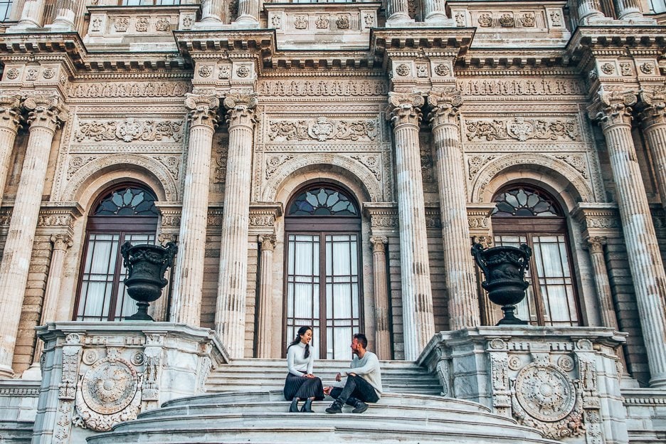 A Guide On How To Spend 4 Days In Istanbul 2.1 L A couple sit on the stairs in front of Dolmabahçe Palace in Istanbul, Turkey