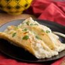 Breakfast Enchiladas Suizas. Scrambled eggs, sausage and Monterey Jack cheese are wrapped in corn tortillas and baked in a green chili sour cream sauce.