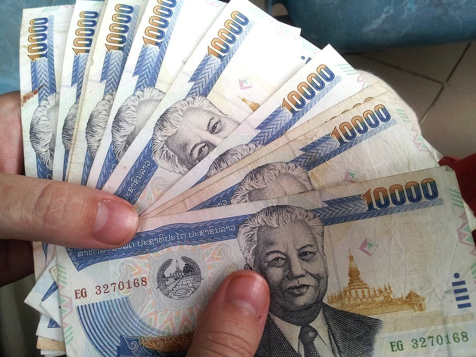 two hands holding Thai baht paper bills