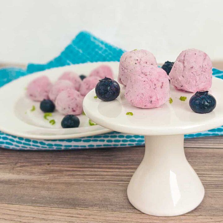 keto blueberry cream cheese fat bombs on a small white plate stand