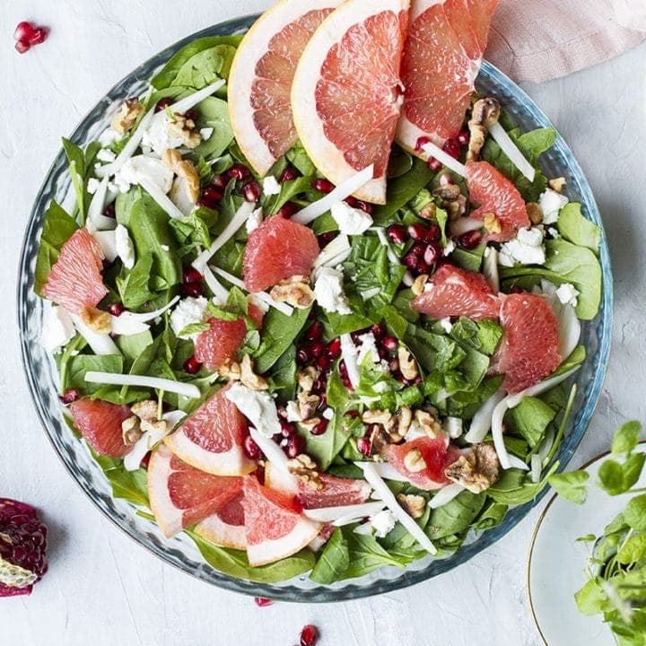 Salad in a shallow pan, seen from above. Garnished with grapefruit slices, fennel and pomegranate.