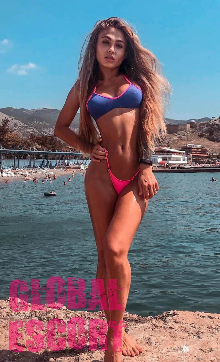 beautiful and sexy tanned girl in a pink bathing suit on the pier