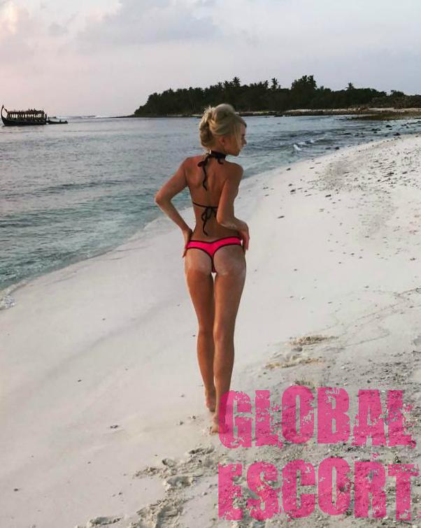sexy escort model Dasha in a pink swimsuit posing on the beach