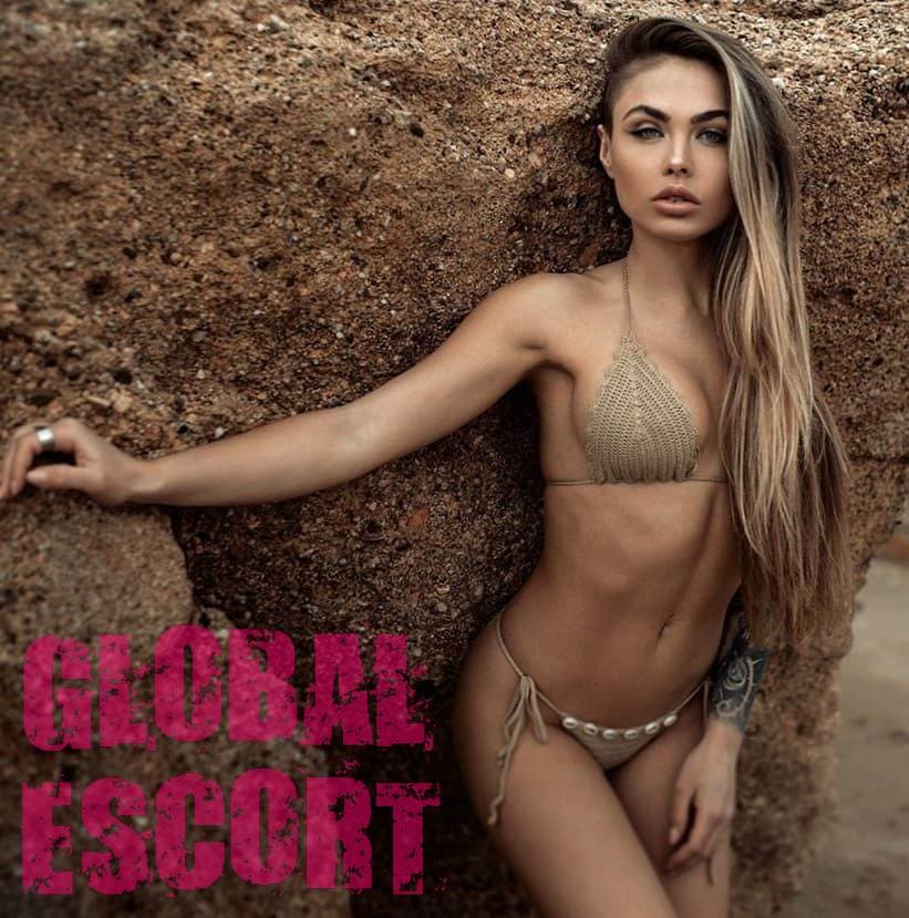 sexy tanned model Valeria in a gold bathing suit on the beach near the rocks