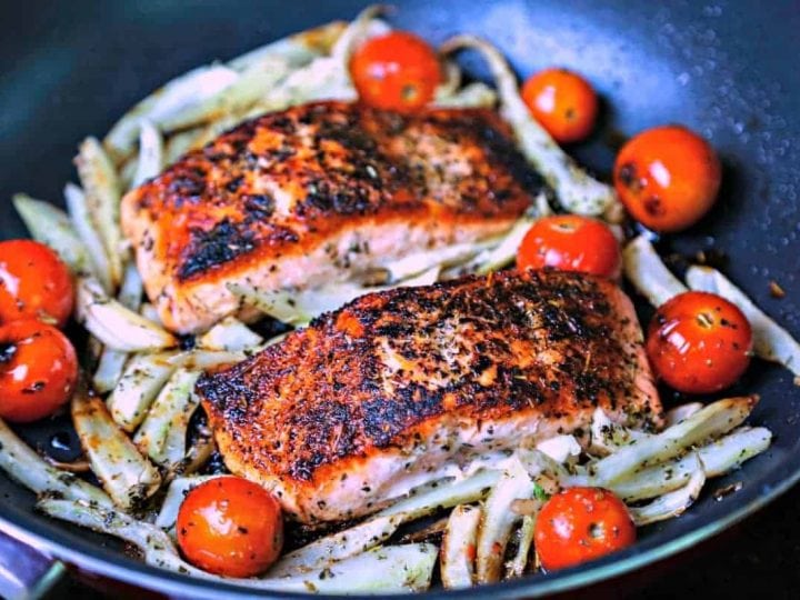 A skillet of Mediterranean Salmon on top of fennel and tomatoes