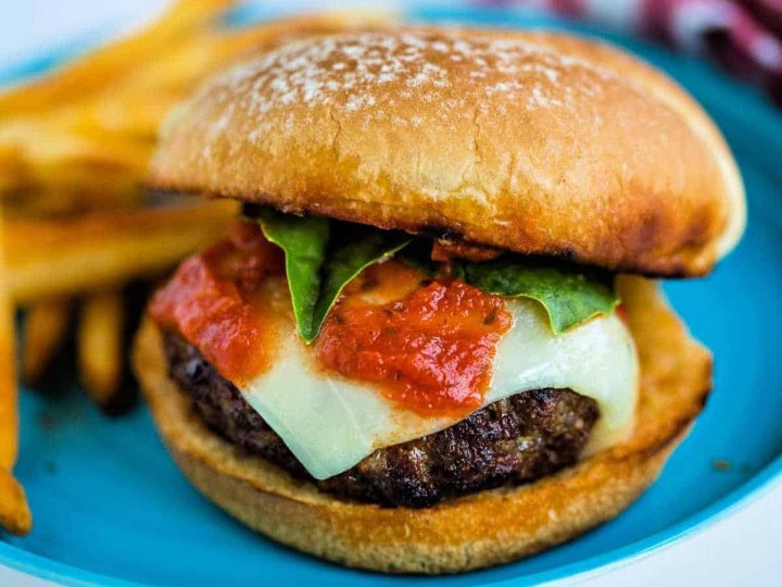 A sandwich on a plate, with French fries and Italian Burger